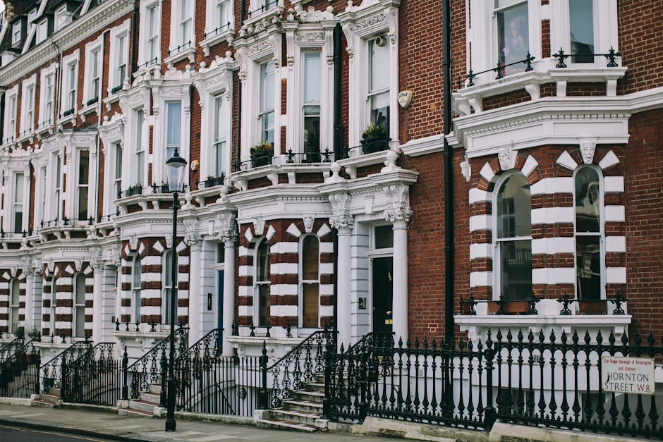 A row of Victorian-style terraced houses constructed with red brick and white decorative architectural features, including ornate window surrounds and cornices. Each property has a small front garden 